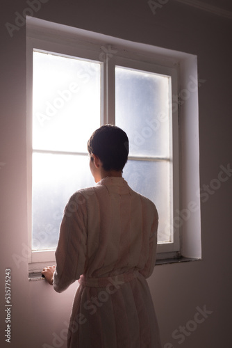 Young woman cancer patient standing in front of hospital window