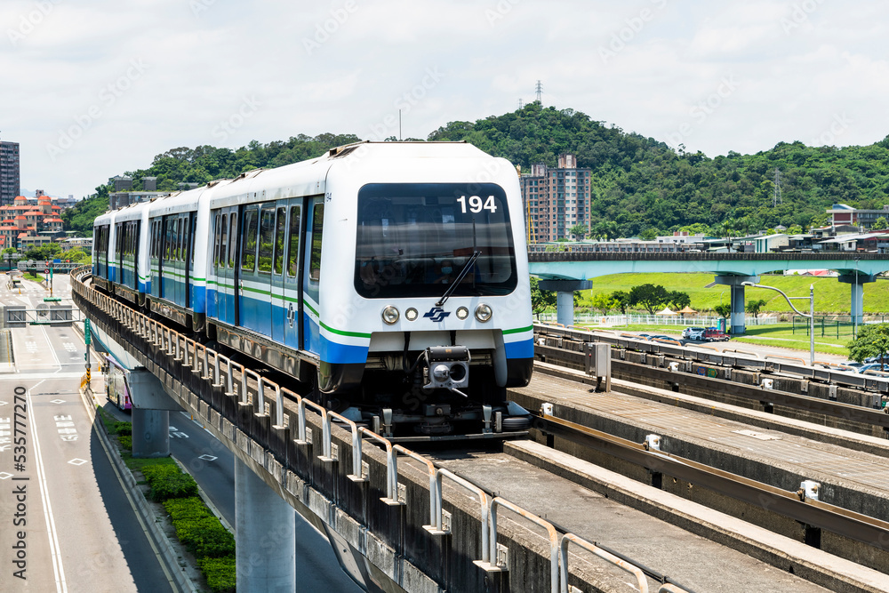 Fototapeta premium Wenhu or Brown line of Taipei MRT in Taiwan. View of a train running on the elevated track of the Taipei subway system under a clear blue sky.