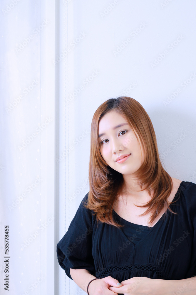 窓際に立ち笑みを浮かべる若い女性 窓際に立ち笑みを浮かべる若い女性