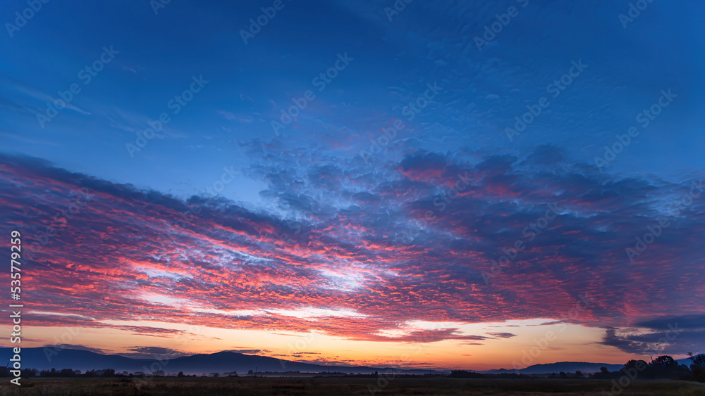 Fototapeta premium Majestic sunset or sunrise landscape with clouds and mountains. olorful sky with clouds