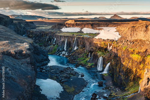 Sunset over Sigoldugljufur with tiny waterfall flowing in canyon on Icelandic Highlands in summer at Iceland