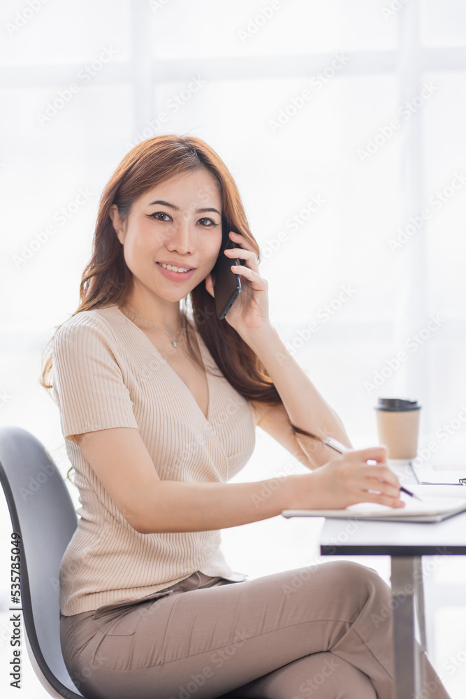 Freelance Smiling young asian business woman using computer laptop working at home Office, Happy business asian woman talking on mobile phone while analyzing weekly schedule in her notebook.
Freelance Smiling young asian business woman using computer laptop working at home Office, Happy business asian woman talking on mobile phone while analyzing weekly schedule in her notebook.