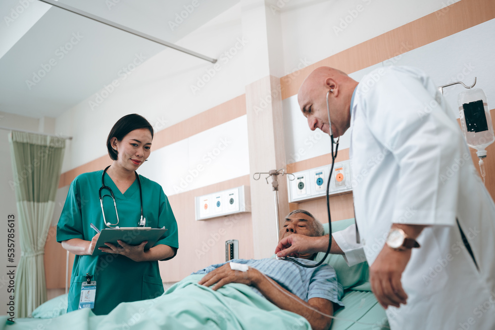professional doctor standing by explain the treatment information via male elderly patient lying in bed in private hospital sickroom. The treatment program is suitable for people to socialize elderly professional doctor standing by explain the treatment information via male elderly patient lying in bed in private hospital sickroom. The treatment program is suitable for people to socialize elderly