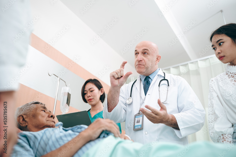 professional doctor standing by explain the treatment information via male elderly patient lying in bed in private hospital sickroom. The treatment program is suitable for people to socialize elderly professional doctor standing by explain the treatment information via male elderly patient lying in bed in private hospital sickroom. The treatment program is suitable for people to socialize elderly