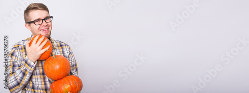 Banner harvesting  halloween and people concept - Man in black glasses holding three pumpkins over white background with copy space