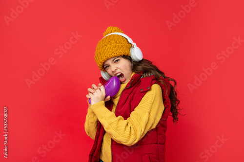 cheerful child in hat listen music in headphones and singing in comb, singing