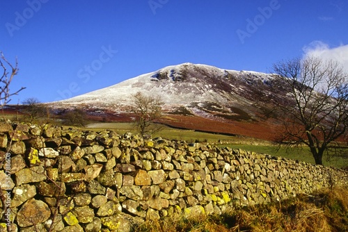 Dry stone wall leading to a snow-covered Herdus fell near Ennerdale Water in the Lake District photo