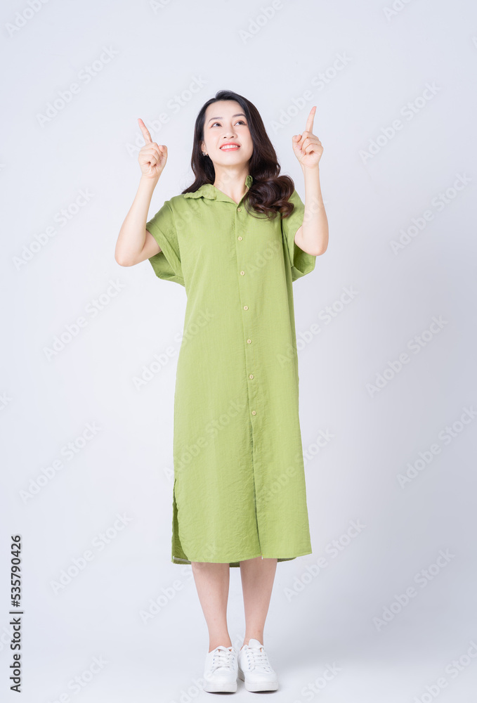 Full length image of young Asian woman wearing green dress on background Full length image of young Asian woman wearing green dress on background