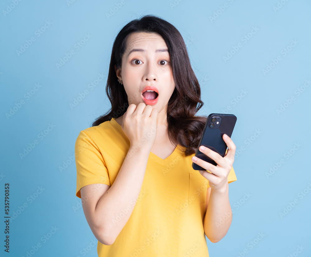 Young Asian woman using smartphone on background Young Asian woman using smartphone on background