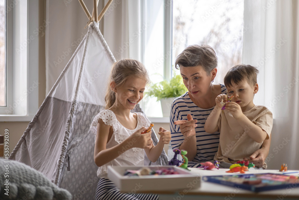 Family mother and kids sculpt dinosaurs from plasticine enjoy weekend Family mother and kids sculpt dinosaurs from plasticine enjoy weekend