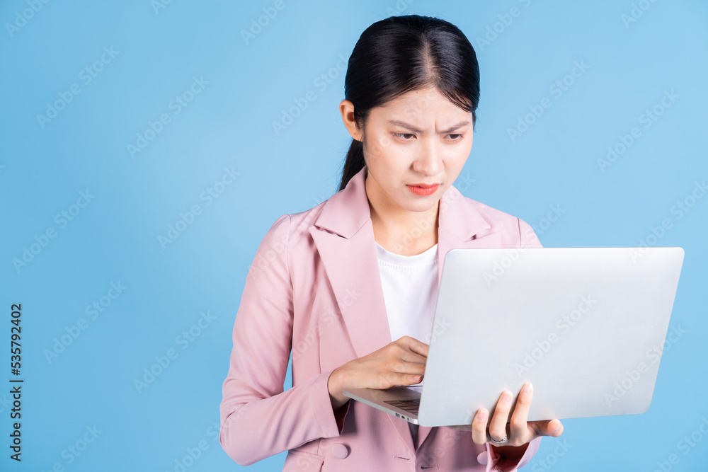 Young Asian business woman using laptop on background Young Asian business woman using laptop on background