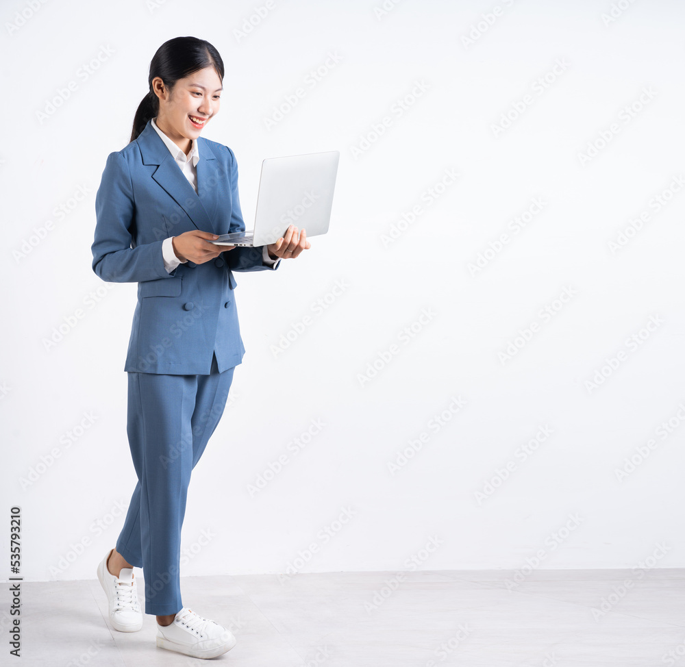 Full length image of young Asian businesswoman holding laptop Full length image of young Asian businesswoman holding laptop