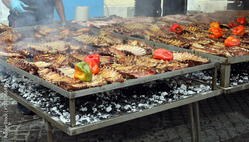 Large barbecue cooking the argentinian Asado, with pork ribs and peppers in the first grill.