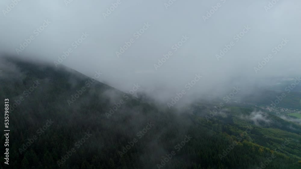 Mountains covered with dense dark forests on a cold foggy morning. White condensation turning into steam after a rainy day. An aerial view of the mysterious nature without people Mountains covered with dense dark forests on a cold foggy morning. White condensation turning into steam after a rainy day. An aerial view of the mysterious nature without people