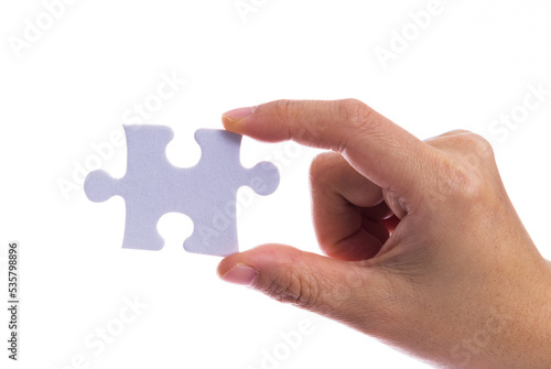 Hand holding a puzzle piece on white background