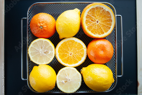 Fresh oranges and lemons in a tray on a table, top view. Citrus fruit concept