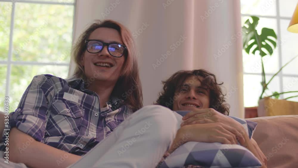 Friends or roommates watching horror movie on couch in living room together. Realtime Friends or roommates watching horror movie on couch in living room together. Realtime