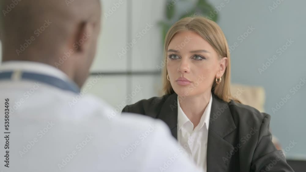 Female Patient Talking with African Doctor in Clinic Female Patient Talking with African Doctor in Clinic
