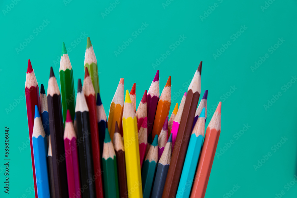 A bunch of colorful pencils on green background A bunch of colorful pencils on green background