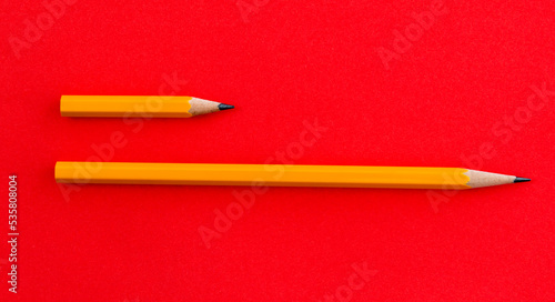 Long and short pencils on red background photo