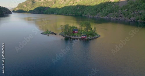 An Isolated View Of A Remote Island With A Red Cottage In Lovrafjorden, Norway. Aerial Drone Orbiting Shot photo