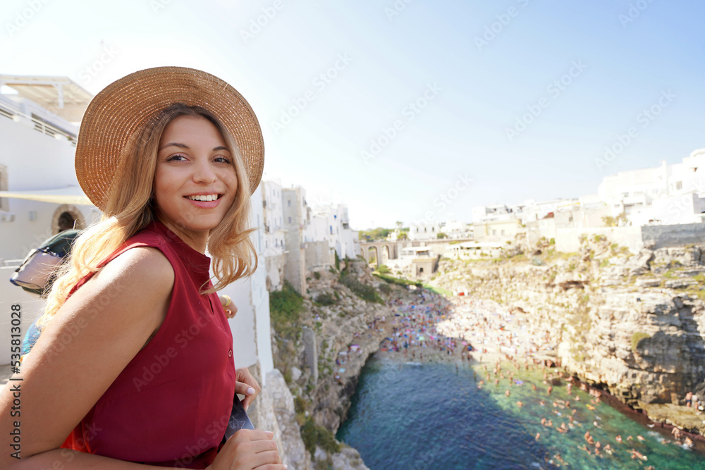 Portrait of tourist girl looking at camera from terrace in Polignano a mare, Apulia, Italy. Wide angle.