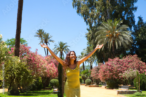 Beautiful young woman with long hair raises her arms to the sky giving thanks to life and the universe. The woman is happy and closes her eyes raising her head upwards. Concept of peace and happiness