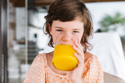 Kid drinking orange juice in cafe photo