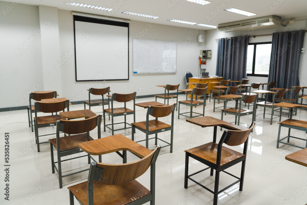 School classroom with many wooden chairs well-arranged in rows with no student School classroom with many wooden chairs well-arranged in rows with no student