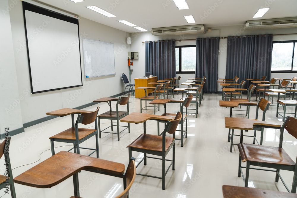 School classroom with many wooden chairs well-arranged in rows with no student School classroom with many wooden chairs well-arranged in rows with no student