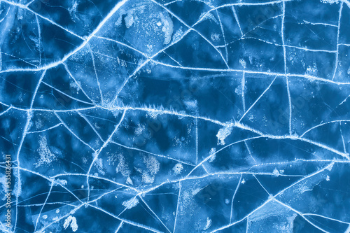 Ice on a frozen river. Background texture of blue ice with cracks in the snow. drone view.