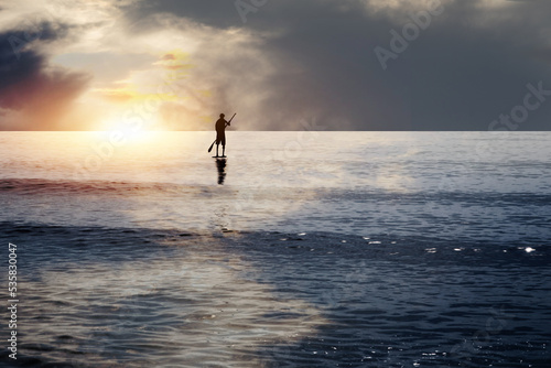 Ein junger Mann auf einem Surfbrett genießt den Sonnenuntergang am Meer © Sergey