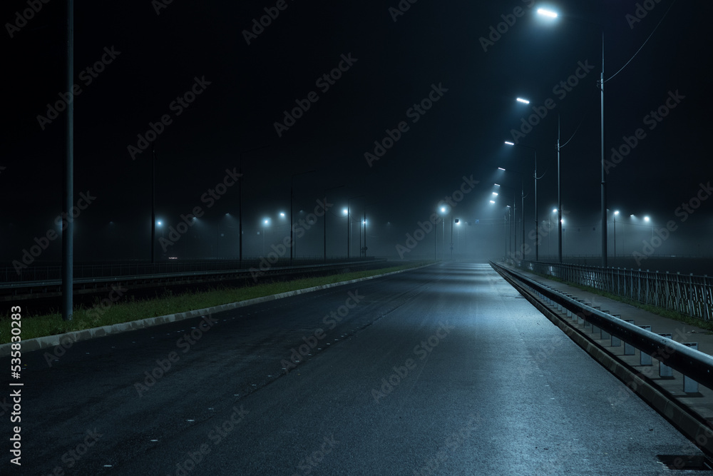 Night foggy highway illuminated by lampposts. Autumn foggy landscape Night foggy highway illuminated by lampposts. Autumn foggy landscape