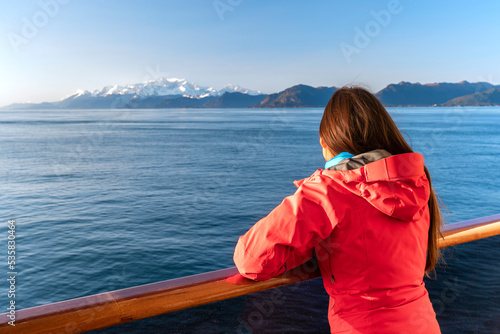 Alaska cruise travel tourist looking at mountains landscape from balcony deck of ship. Inside passage Glacier bay scenic vacation travel woman enjoying scenery from boat