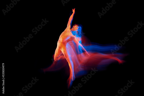 Aspiration. Solo performance of flexible male ballet dancer dancing isolated on dark background in glowing colorful neon light. Grace, art, beauty