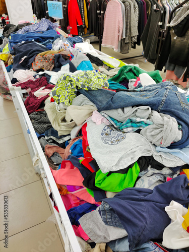 In the second-hand store, there are baskets with a variety of clothes in bulk for different tastes.