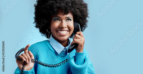 Telecom landline, phone or black woman talking, communication on blue mockup studio background. Happy, smile or young African girl model speaking to contact on vintage phone with mock up space photo