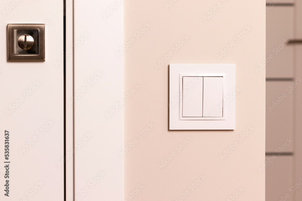 White electrical switch on beige wall next to the door in modern apartment White electrical switch on beige wall next to the door in modern apartment