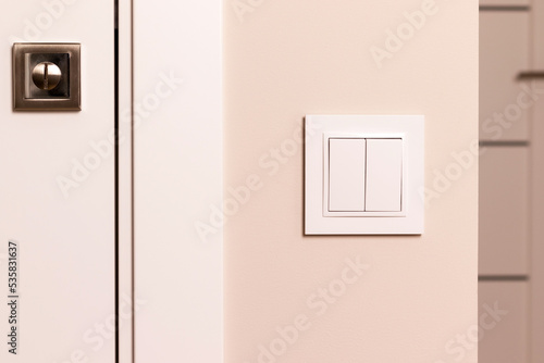 White electrical switch on beige wall next to the door in modern apartment