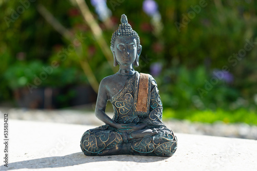 Buddha statue near house in front of garden.