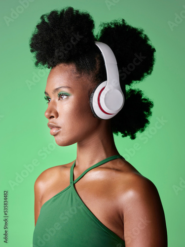 Black woman with headphones listening to music or podcast on green studio background mockup advertising and marketing. African gen z girl with audio for youth lifestyle or streaming service mock up