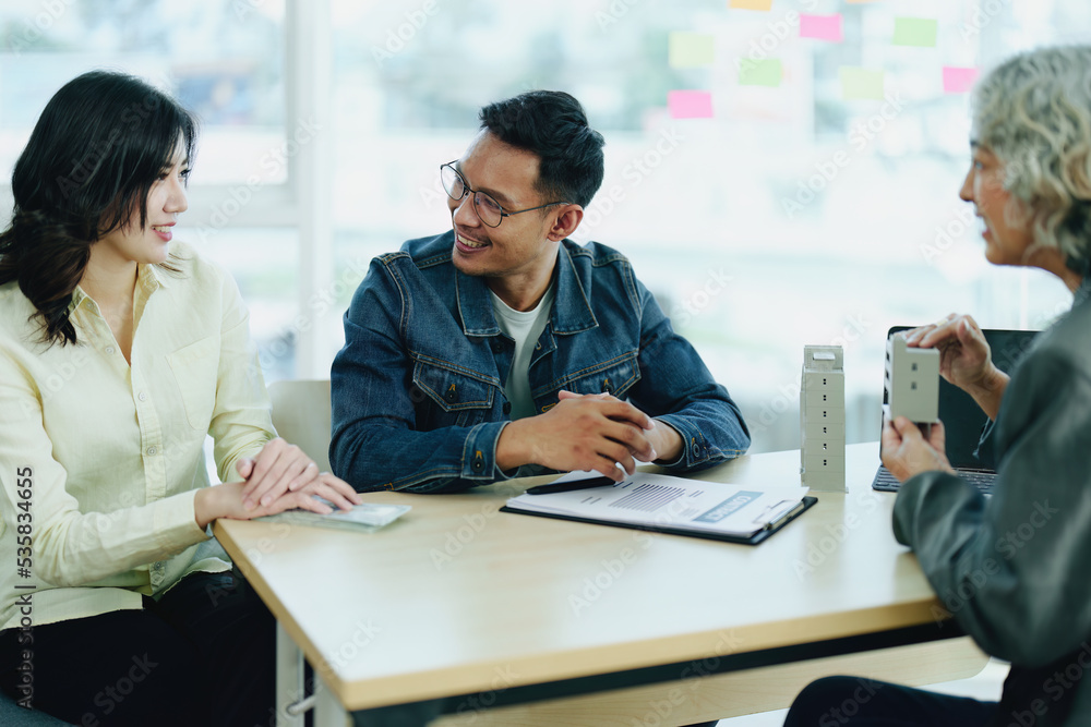 Fototapeta premium Guarantee Insurance Sign a contract, couple a smiling couple is signing a contract to invest in real estate with the Mortgage officer with the bank