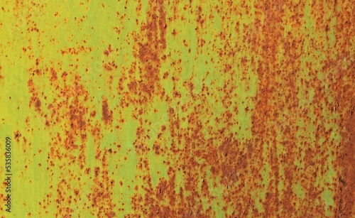 Background and texture of metallic wall. Shabby and scaly backdrop, colored in fiery yellow color. Old rusty metal surface with faded uneven color. Abstract sketches and colors of old walls and fences