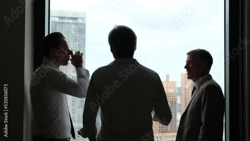 silhouette of a business man standing in the morning talking in a dark room on a high rise in the city	