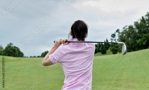 Woman golf player swinging golf club