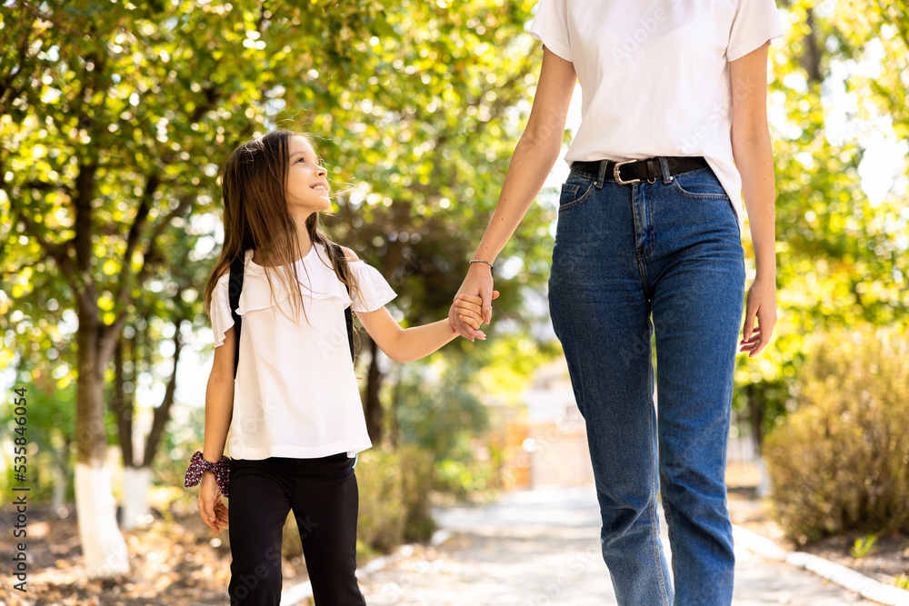 Fototapeta premium Mother holding her daughter's hand and heading to school on the first day of school.