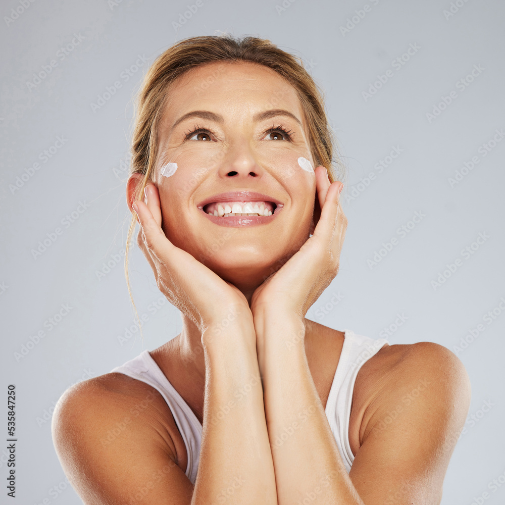 Face, beauty and skincare with a beautiful woman in studio on a gray background for antiaging or healthcare. Health, body and care with a mature female applying lotion or cream to her skin Face, beauty and skincare with a beautiful woman in studio on a gray background for antiaging or healthcare. Health, body and care with a mature female applying lotion or cream to her skin