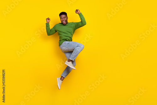 Full length body size view of attractive cheery guy jumping rejoicing attainment isolated over bright yellow color background photo