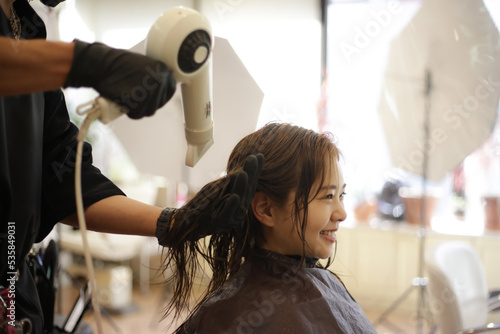 女性の髪にドライヤーをかける男性美容師