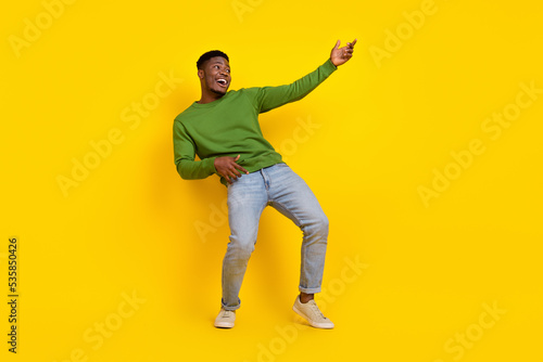 Full length body size view of attractive carefree cheerful guy playing invisible guitar isolated on bright yellow color background